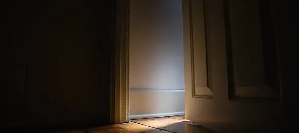 Light spilling through a partially open doorway into a quiet room.