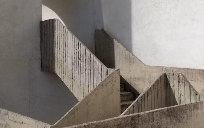 Minimalist concrete staircase turning a corner, with soft light and geometric shadows.